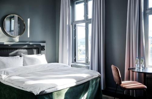 a bedroom with a bed and a table and a mirror at Hotel Filip in Oslo