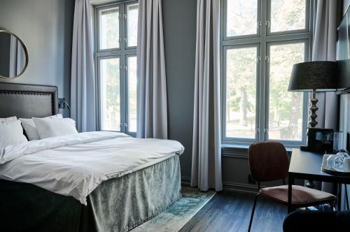 a bedroom with a bed and a desk and windows at Hotel Filip in Oslo