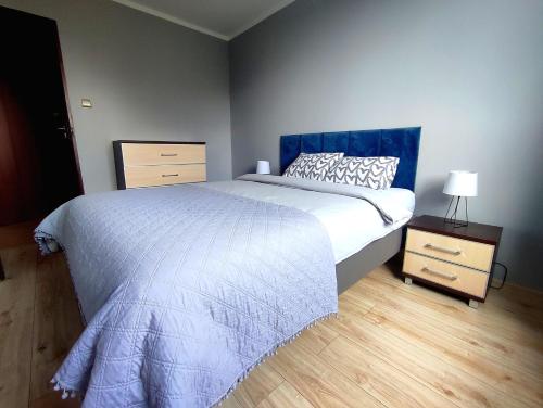 a bedroom with a large bed with a blue headboard at Parkcity Chorzów in Chorzów