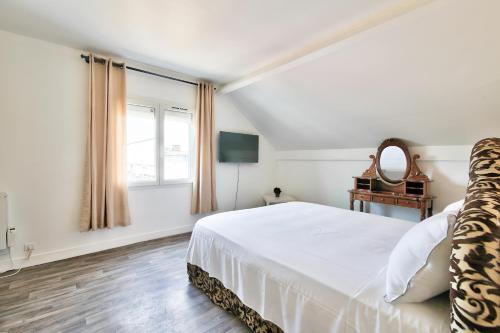 a white bedroom with a large bed and a mirror at Appartement meublé Dugny in Dugny