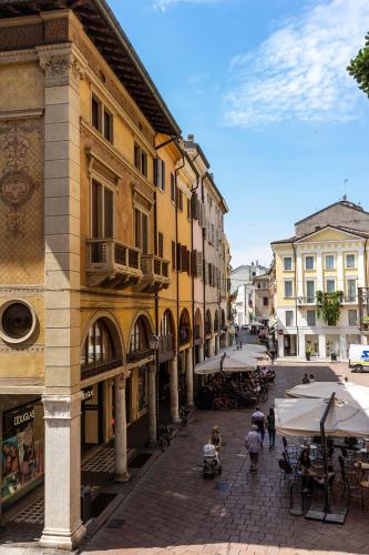 a city street with buildings and tables and umbrellas at CasaLonghi in Mantova