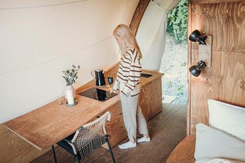 a woman standing in a kitchen in a tiny house at WOW magisches Luxus Glamping mit Pool im Paradies in Bad Salzdetfurth