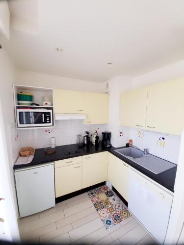 une cuisine avec des armoires blanches et des comptoirs noirs dans l'établissement Nouveau monde, à La Rochelle