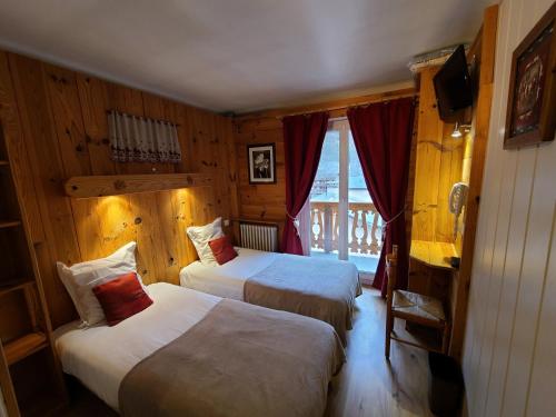 a hotel room with two beds and a window at Hôtel du Centre in Valloire