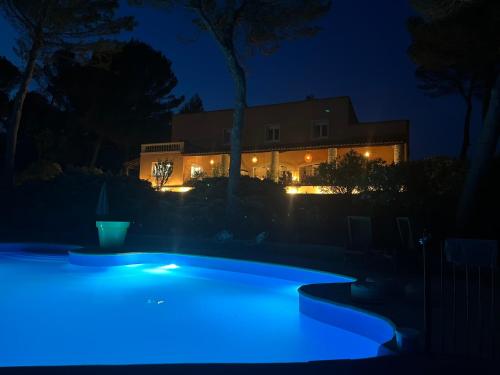 a pool with blue lights in front of a house at night at Hôtel La Pinède in Saint-Marcellin-lès-Vaison