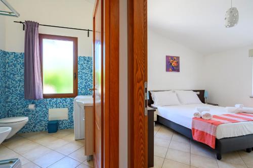 a bedroom with a bed and a bathroom with a toilet at I Girasoli in Bari Sardo