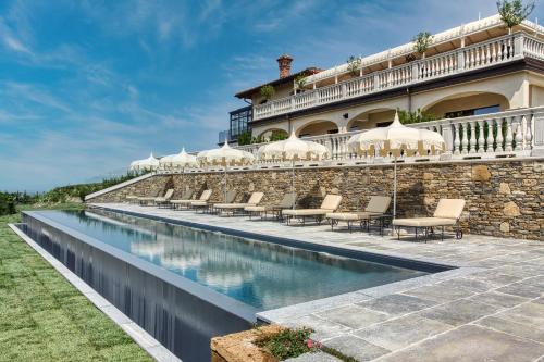 einem Pool vor einem Gebäude mit Stühlen und Sonnenschirmen in der Unterkunft Relais Le Due Matote in Bossolasco