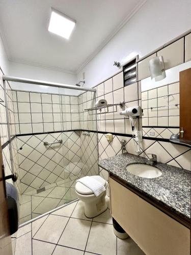 a bathroom with a toilet and a sink and a shower at Hotel Bons Tempos in Rio Verde