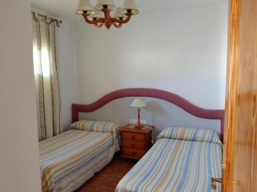 1 dormitorio con 2 camas y mesa con lámpara en Apartamento Cerca de la Playa con wifi, en San José