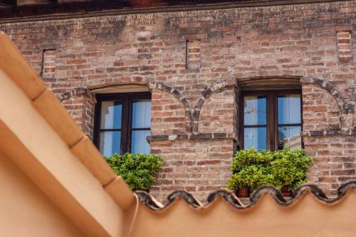 three windows on a brick building with plants at CasaLonghi in Mantova