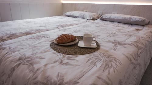 a bed with a tray of croissants and a cup of coffee at BUNGALOW LOS ARCOS in Maspalomas