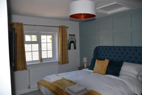 a bedroom with a bed with a blue headboard and a window at The Thorold in Marston