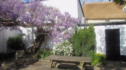 a wooden bench in front of a building with purple flowers at Thorverton Arms in Exeter