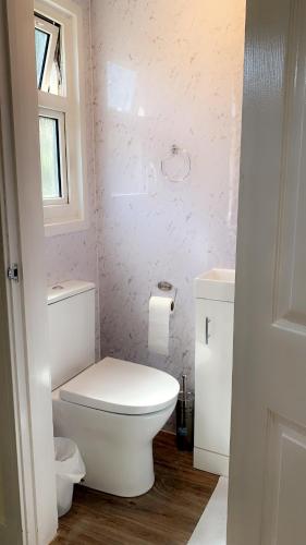 a bathroom with a white toilet and a window at Mon Repos Heathrow - Hatton Cross Station 2 Stops from Heathrow Underground Free WiFi Free Parking Free Refreshments in New Bedfont