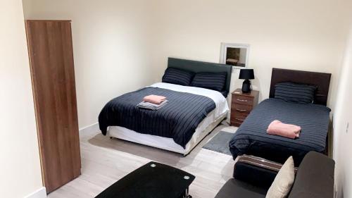 a bedroom with two beds and a chair at Mon Repos Heathrow - Hatton Cross Station 2 Stops from Heathrow Underground Free WiFi Free Parking Free Refreshments in New Bedfont