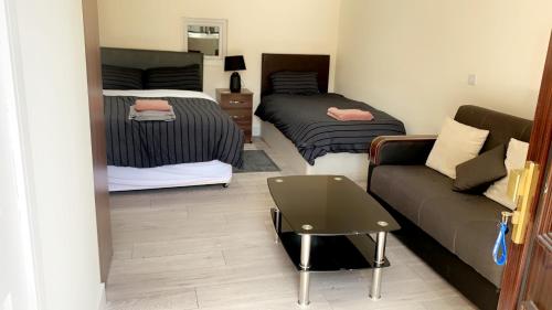 a living room with two beds and a couch at Mon Repos Heathrow - Hatton Cross Station 2 Stops from Heathrow Underground Free WiFi Free Parking Free Refreshments in New Bedfont