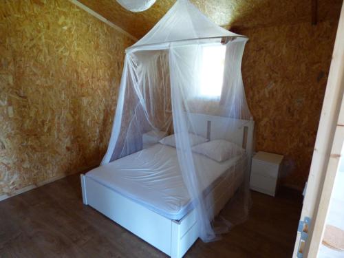 Cette chambre comprend un lit blanc à baldaquin. dans l'établissement Le Carbet Vendéen, à Bouillé-Courdault