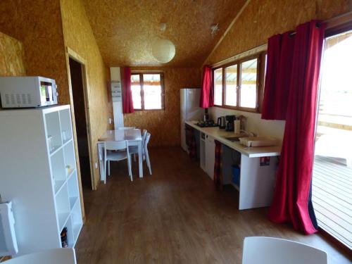 a kitchen with a table and a kitchen with red curtains at Le Carbet Vendéen in Bouillé-Courdault