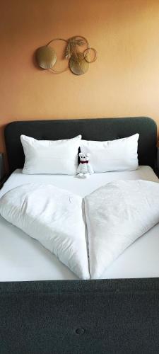 a bed with white sheets and a stuffed animal on it at Pension Fellis in Vols am Schlern