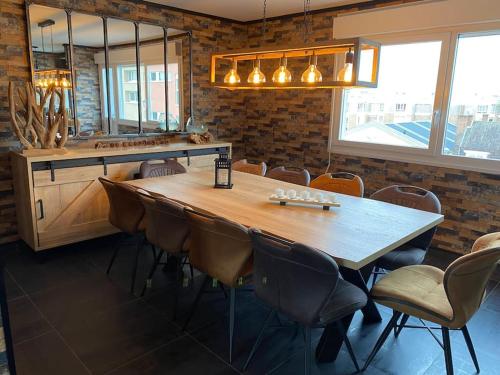 a dining room with a large wooden table and chairs at Au petit bonheur imprévu in Douai