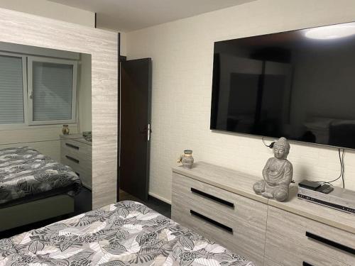 1 dormitorio con 1 cama y TV grande en la pared en Au petit bonheur imprévu, en Douai