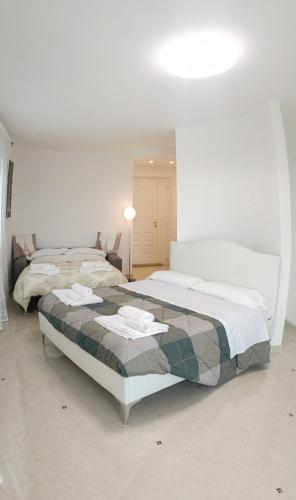 a white bedroom with two beds and a lamp at Villa Carmen Resort in Campobasso