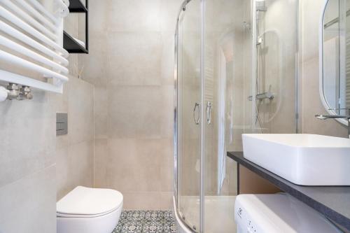 a bathroom with a shower and a toilet and a sink at Brzeźno Studio Deluxe in Gdańsk