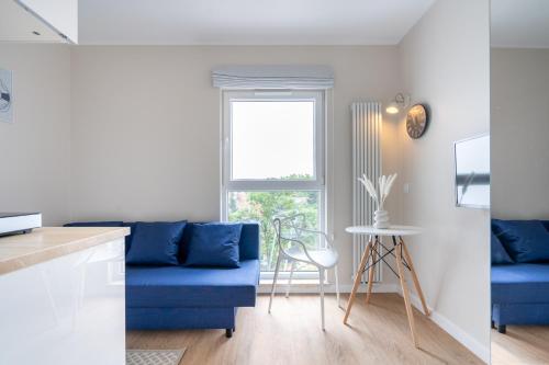 uma sala de estar com um sofá azul e uma janela em Brzeźno Studio Deluxe em Gdansk
