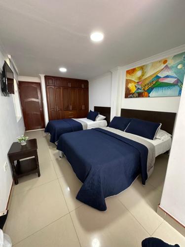 a bedroom with two beds with blue sheets in it at Hotel Paipa Inn in Paipa