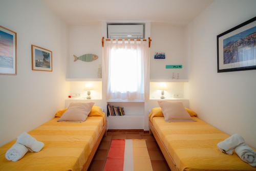 twee bedden in een kleine kamer met een raam bij Can Tamarix in La Savina