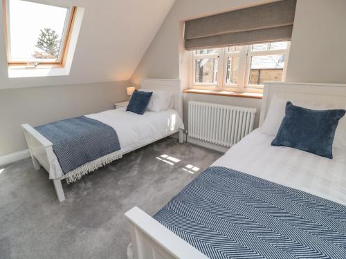 two beds in a room with two windows at Willow Cottage in Morpeth