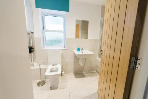 a bathroom with a toilet and a sink and a window at Stylish Open Plan City Apartment in Bath