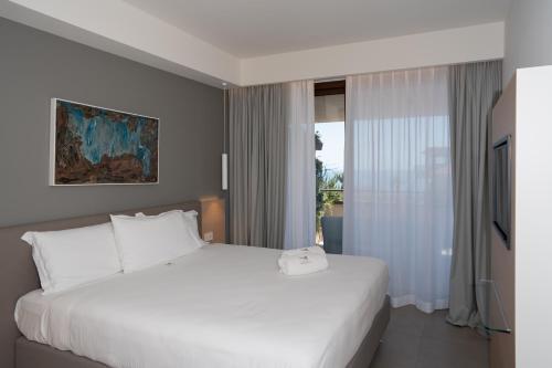 a bedroom with a white bed and a window at Sicilia's Art Hotel & Spa in Acitrezza