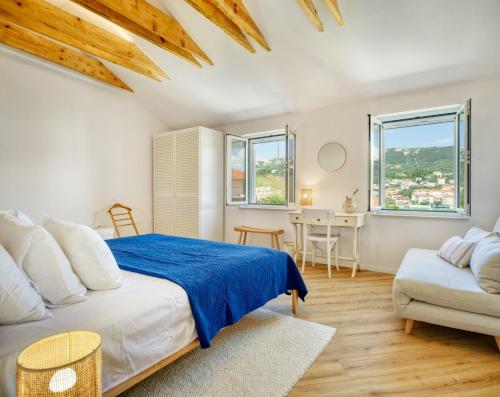 a bedroom with a bed and a couch and windows at House Gajarda in Rab