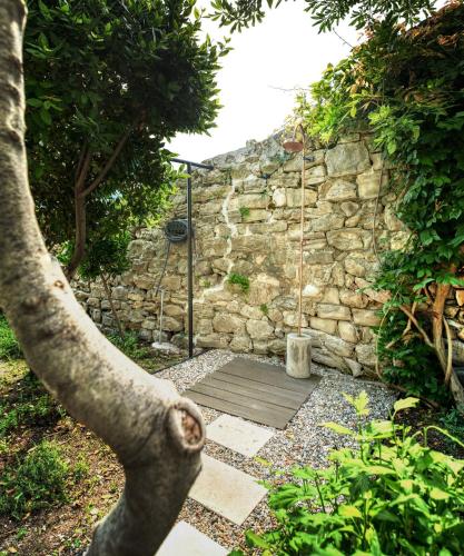 a garden with a stone wall and a fence at House Gajarda in Rab