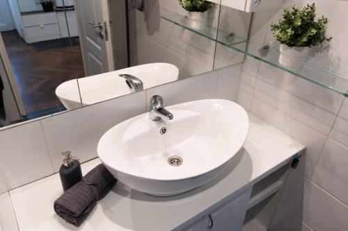 een badkamer met een witte wastafel en een spiegel bij Bright & Shine Apartment in Boedapest