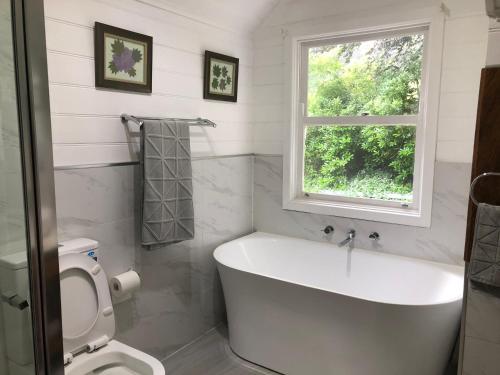 a bathroom with a white tub and a window at The Whitehouse in Sassafras