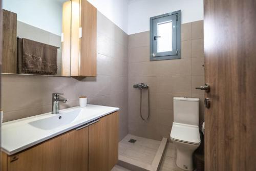 Un baño con lavabo, inodoro y ventana. en Extreme House, en Archangelos