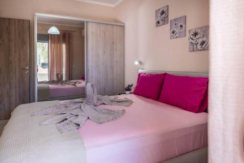 um quarto com uma grande cama branca com almofadas cor-de-rosa em Extreme House em Archangelos
