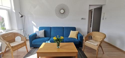 um sofá azul numa sala de estar com cadeiras e uma mesa em Słoneczny apartament blisko jeziora i gór em Bielawa
