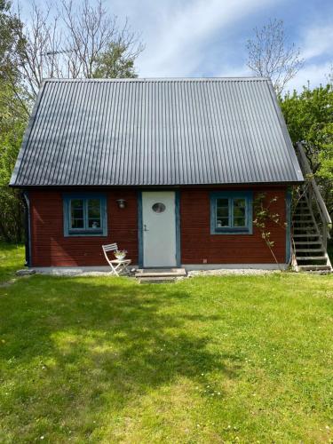 una pequeña casa roja con una puerta blanca en un patio en Gårdshus i lummig trädgård Klintehamn, en Klintehamn