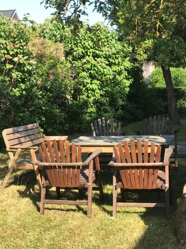 3 sillas de madera y una mesa de picnic en el césped en Gårdshus i lummig trädgård Klintehamn, en Klintehamn