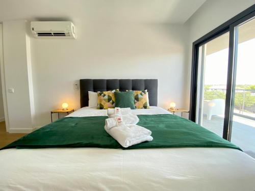 una camera da letto con un letto grande con asciugamani sopra di Tavira Grand Balcony With Pool by Homing a Tavira
