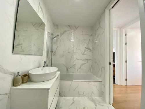 un bagno bianco con vasca e lavandino di Tavira Grand Balcony With Pool by Homing a Tavira