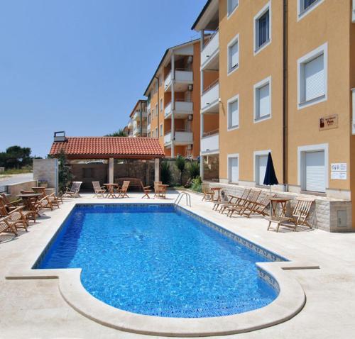 a swimming pool with tables and chairs next to a building at Apartments Flora in Premantura