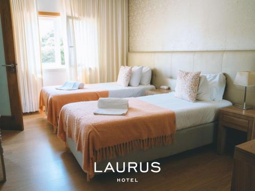 um quarto de hotel com duas camas com lençóis laranja em Laurus Hotel na Lourinhã