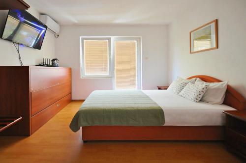a bedroom with a bed and a dresser and a television at Apartments Nada in Budva