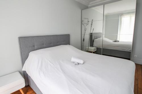 a bedroom with a white bed with a mirror at Charming and luminous 2br with balcony - Boulogne-Billancourt - Welkeys in Boulogne-Billancourt