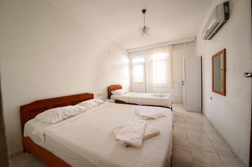 two beds in a room with white walls at Fethiye Apart Otel in Fethiye