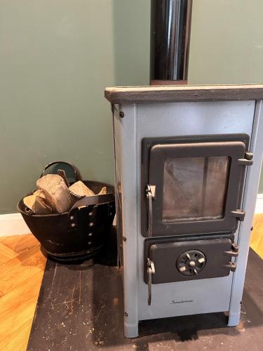 a wood stove with a basket of logs at Casa Clementine - Boutique Guesthouse in Veldhoven